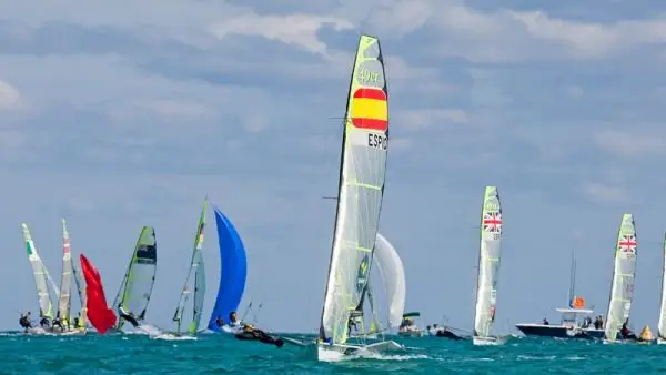 A Spanish 49er skiff leads a crowded fleet during a regatta, showing how dynamic Olympic sailing is