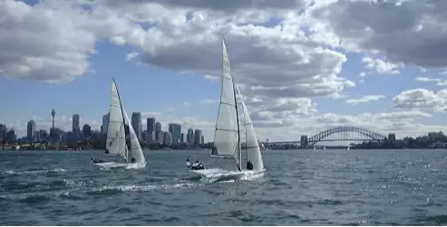 Two 49er skiffs sailing on Sydney Harbour, with the city skyline and Harbour Bridge behind